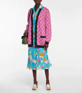 Dark-skinned woman wearing a blue floral dress with a pink monogrammed cardigan. | luxury homes by brittany corporation