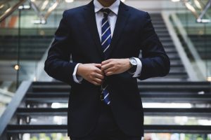 Photo of a man in formal suit and tie, standing in front of the stairs - Real estate sales professionals - Luxury Homes by Brittany Corporation