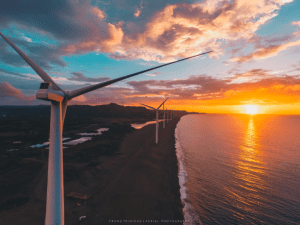 Photo of a windmill facing the sea with a golden sunset - Brittany Corporation