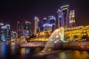 Singapore skyline at night merlion water releasing water luxury condominium behind them for vegan travel | luxury homes by brittany corporation