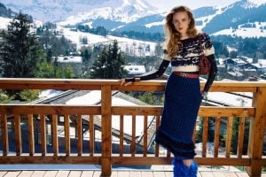 Caucasian lady wearing knitted top and blue fluffy skirt with a red bag and blue fluffy boots in front of a mountain | luxury homes by brittany corporation