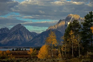 grand teton mountain view with orange leaved trees and white trunks over seeing luxury home lake | Luxury Homes by Brittany Corporation