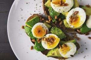 omega rich avocado toast with soft boiled egg cut in half with freshly ground black pepper on a table in a luxury condominium by brittany cororation | luxury homes by brittany corporation