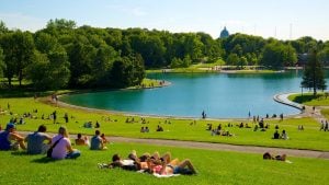 people lying down on the green grass overlooking the lake in mount royal park luxury condos near it | Luxury homes by brittany corporation