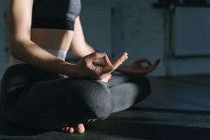 person in lotus pose doing yoga in black yoga pants and sports bra relaxing in a luxury homes by brittany corporation | luxury homes by brittany corporation