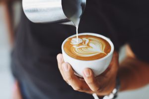 Man pouring milk into coffee to create latte art