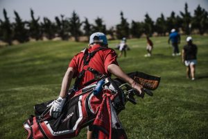 caddy wearing red carrying a red golf bad | luxury homes by Brittany corporation