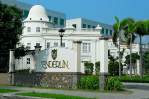 Enderun entrance white half wall with luxury gold enderun plate and logo white buildings behind the logo | luxury homes by brittany corporation