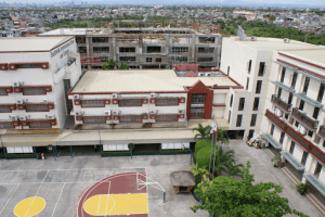 aerial view of low rise red and white building with basketball court 3 point area painted red and yellow with plants on the right and 6 floor vertical building | luxury homes by brittany corporation