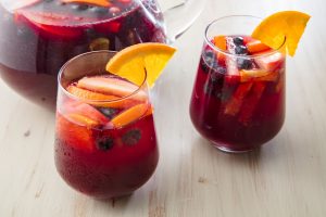 2 cups filled with fruity sangria and the punch bowl on a wooden table in a luxury house and lot | Luxury Homes by Brittany Corporation