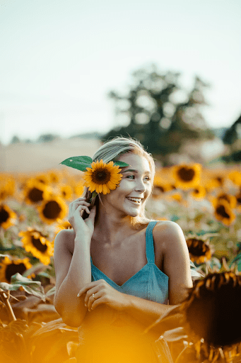 Caucasian woman in Sunflower Garden wearing a blue dress taking a photo for the golden hour | Luxury Homes by Brittany Corporation