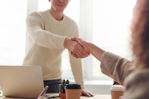 man in white shaking hands with woman in brown closing luxury homes | Luxury Homes By Brittany Corporation