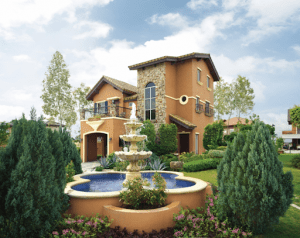 orange luxury home with water fountain and shrubs | luxury homes by brittany corporation