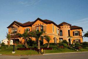 orange luxury mansion with palm trees surrounding it in portofino alabang | luxury homes by brittany corporation