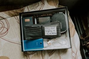 Photo of an old wallet and digital devices placed inside a blue box without cover. | luxury homes by brittany corporation