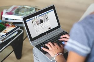 Woman browsing Facebook on laptop | Luxury homes by brittany corporation