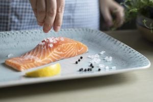 A person seasoning a fillet of salmon food photography recipe idea | luxury homes by brittany corporation