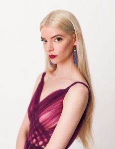 anya taylor joy with blonde hair blue dangling earrings and a purple chiffon dress | luxury homes by brittany corporation
