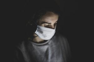 man wearing facemask in a dark room | luxury homes by brittany corporation
