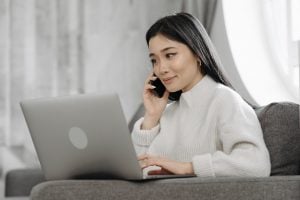 mom trying to contact someone through the phone while looking at a laptop | luxury homes by brittany corporation