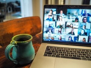 online meeting on a silver laptop with a green mug | luxury homes by brittany corporation