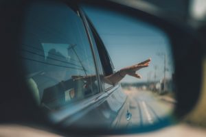 side mirror of a car reflecting a persons hand out the window | luxury homes by brittany corporation