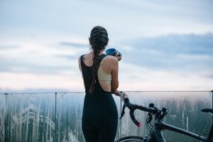 woman taking a rest on a railing while holding a mug and her bike | luxury homes by brittany corporation