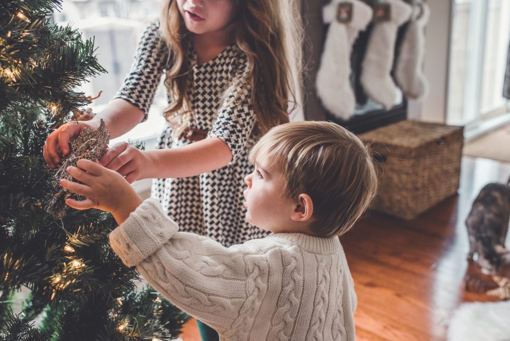 neighborhood to live Kids decorating a Christmas tree. | luxury homes by brittany corporation