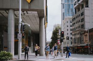 People waiting for the crossing light to turn green at an intersection. | luxury homes by brittany corporation