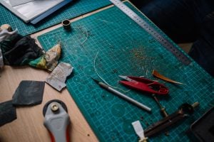 crafting table with x-acto knife and pliers on top of green cutting board | luxury homes by brittany corporation