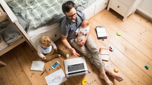 dad with two babies while working on the floor | luxury homes by brittany corporation