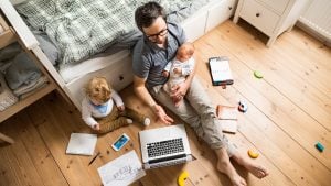 dad with two babies while working on the floor | luxury homes by brittany corporation