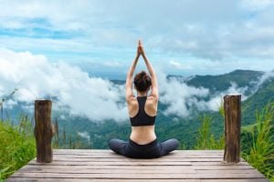 lady at the edge of a mountain doing yoga | luxury homes by brittany corporation