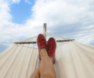 man lying down on a hammock with red shoes | luxury homes by brittany corporation