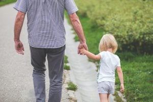 old man grandpa holding the hand of little blonde girl | luxury homes by brittany corporation