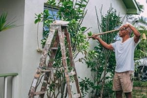 old man wearing white shirt painting the outside of a house | luxury homes by brittany corporation