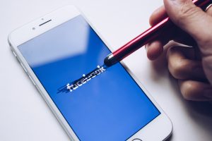 person erasing the logo of facebook on their phone | luxury homes by brittany corporation