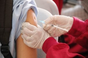 person in blue shirt being vaccinated by person in red PPE | luxury homes by brittany corporation