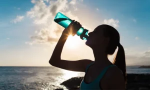 woman drinking water from a bottle against the sun | luxury homes by brittany corporation