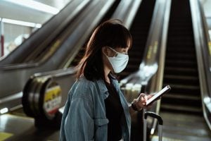 woman in front of escalator wearing a facemask holding a phone | Opening of Cinemas and Theaters in the Philippines