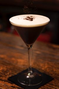 Photo of a chocolate-colored mocktail on a clear martini glass. | luxury homes by brittany corporation