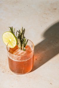 Photo of a light-red colored mocktail on a clear glass. | luxury homes by brittany corporation