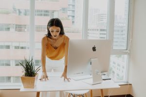 Photo of a woman wearing a yellow tank top and standing in front of a computer. | luxury homes by brittany corporation