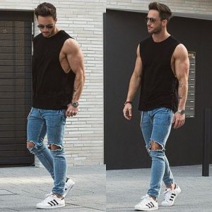 man in ripped jeans and sleeveless shirt showing off his side muscles | luxury homes by brittany corporation