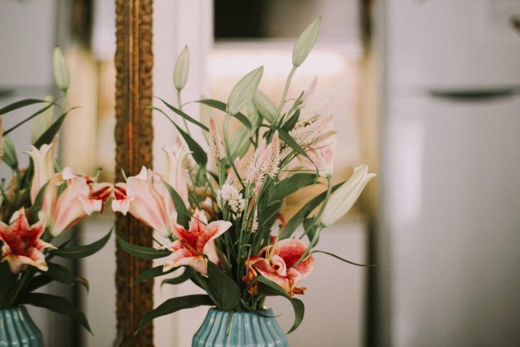 Adding Floral Accents To Real Estate Decor Photo of pin, white, and green flowers, arranged in a blue ceramic vase