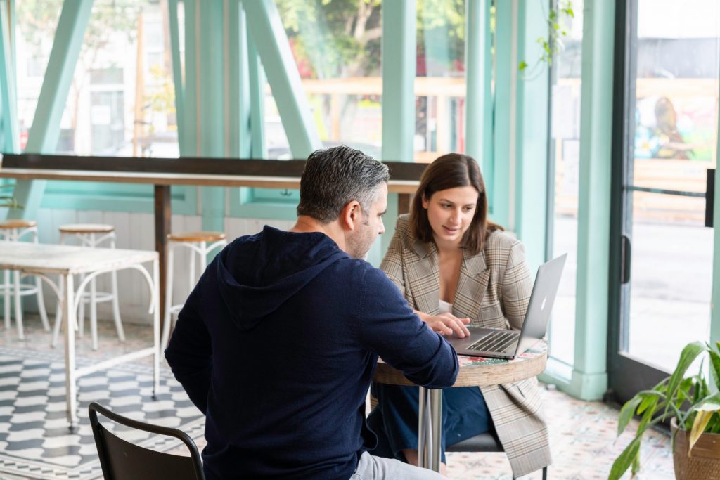 Photo of two women smiling at each other while sitting on a leather chairs in front of a table. - Why Does Your Sales Presentation Matter 