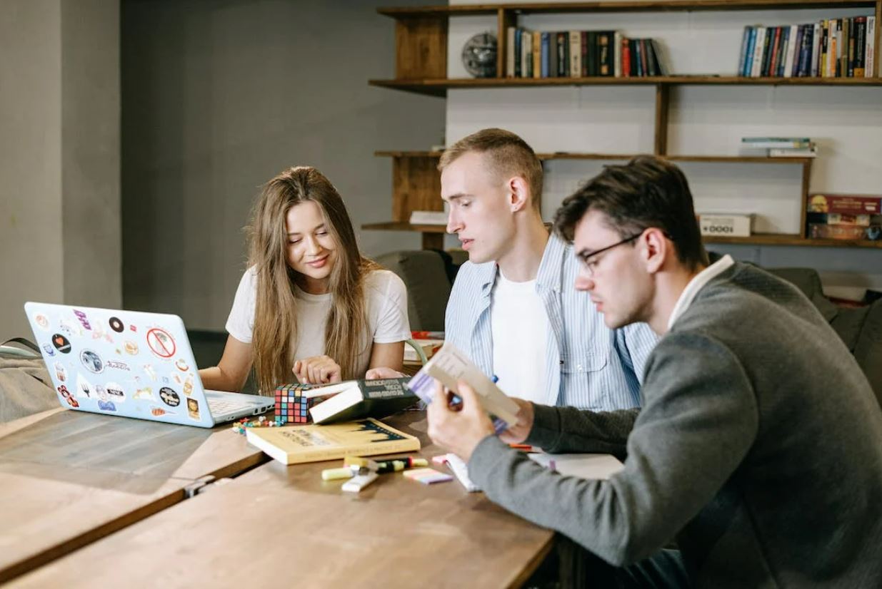 Photo of 3 people discussing about a book