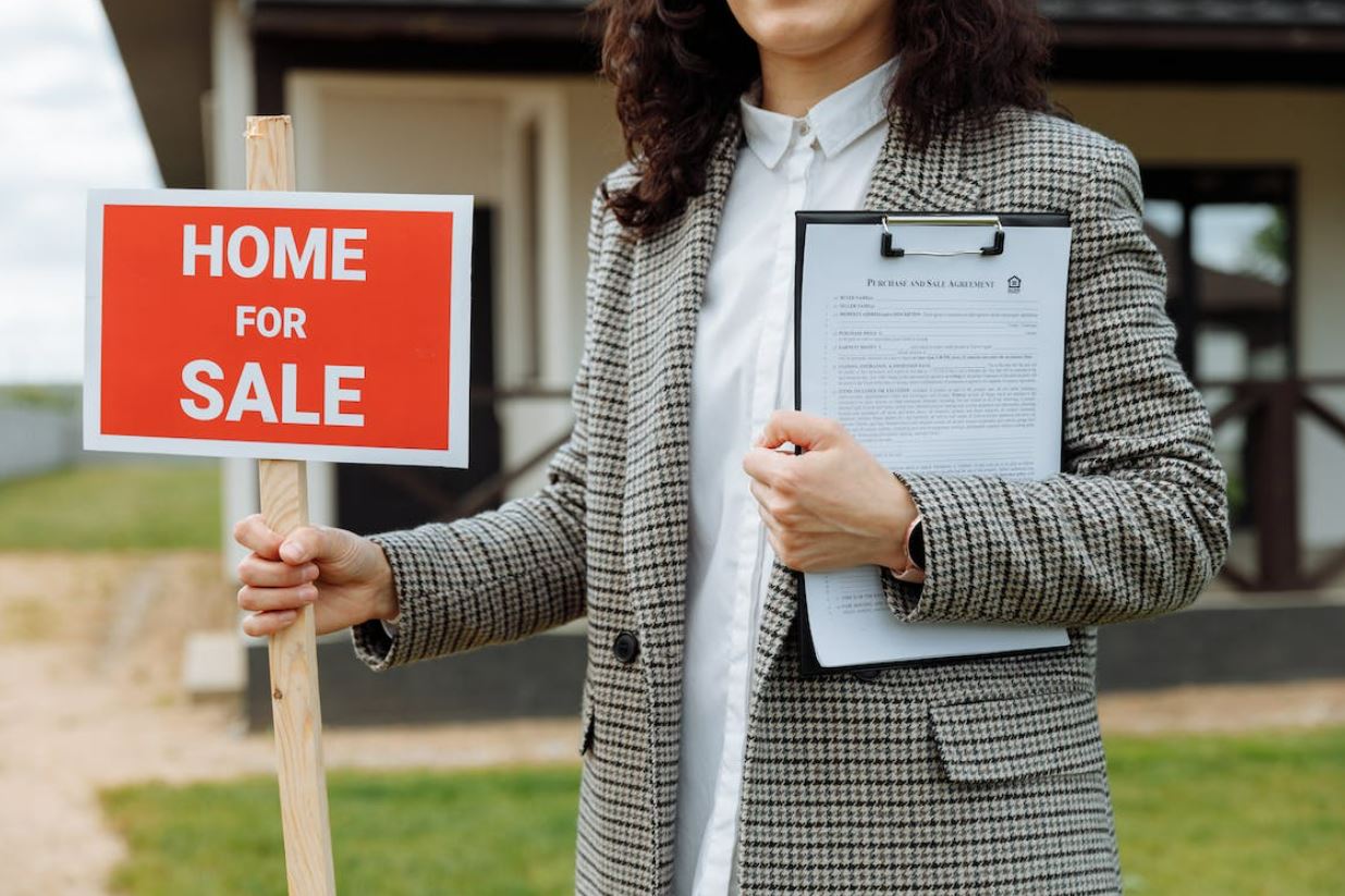 Photo of a girl holding a home for sale sign