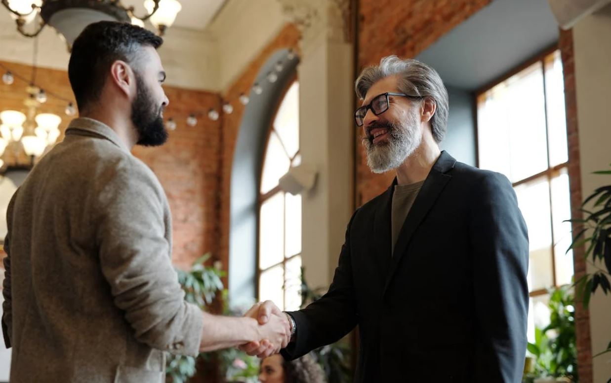 Photo of two men shaking hands while smiling