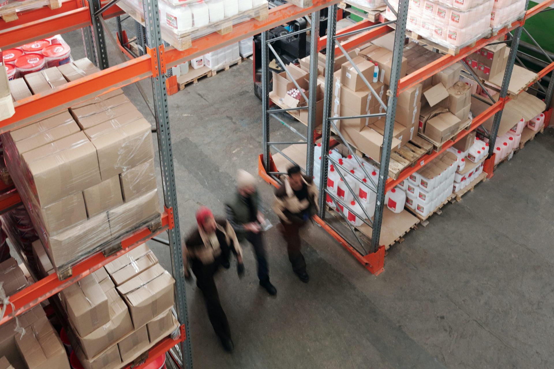 Photo of a warehouse with 3 personnel walking